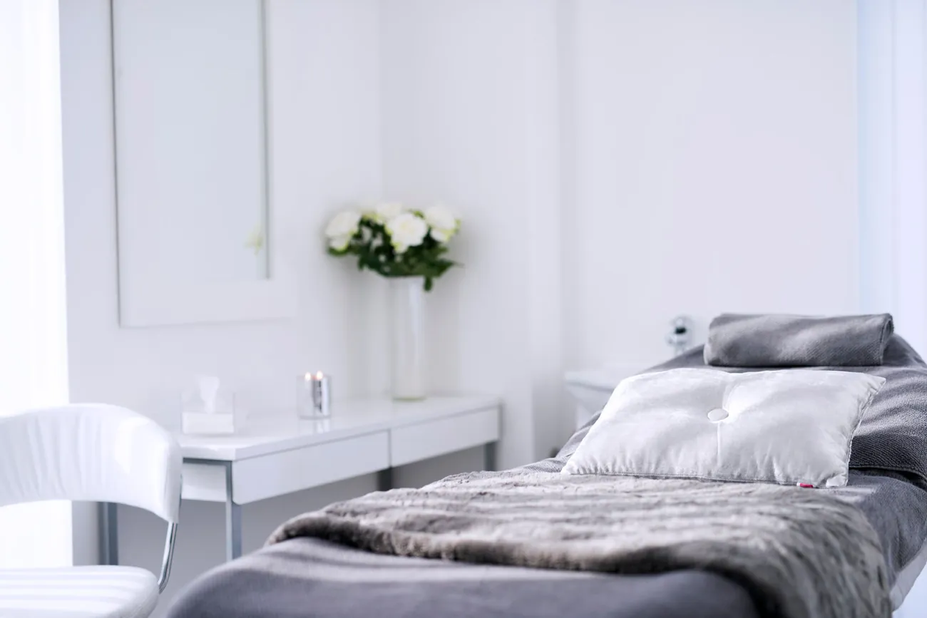 Lyst og innbydende behandlingsrom med benk, tepper og friske roser